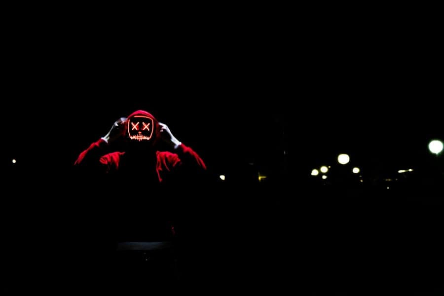 A tall hooded figure looming over a walkway in a night yard display