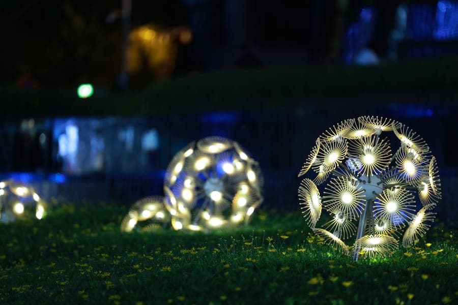 A wide domed inflatable glowing blue on a lawn at night